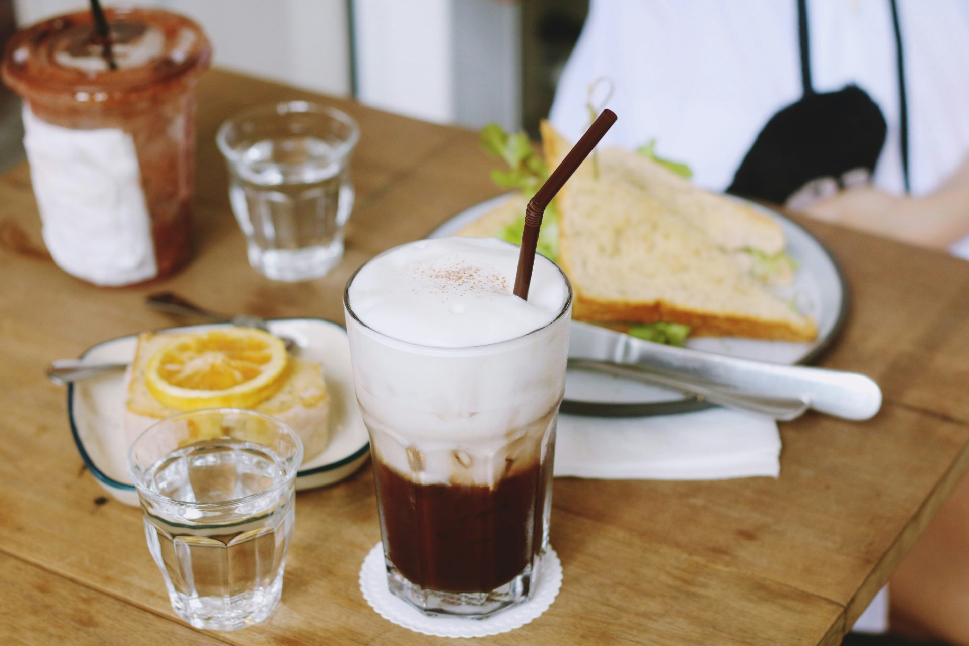 Foamy iced coffee, sandwich, and dessert plate.