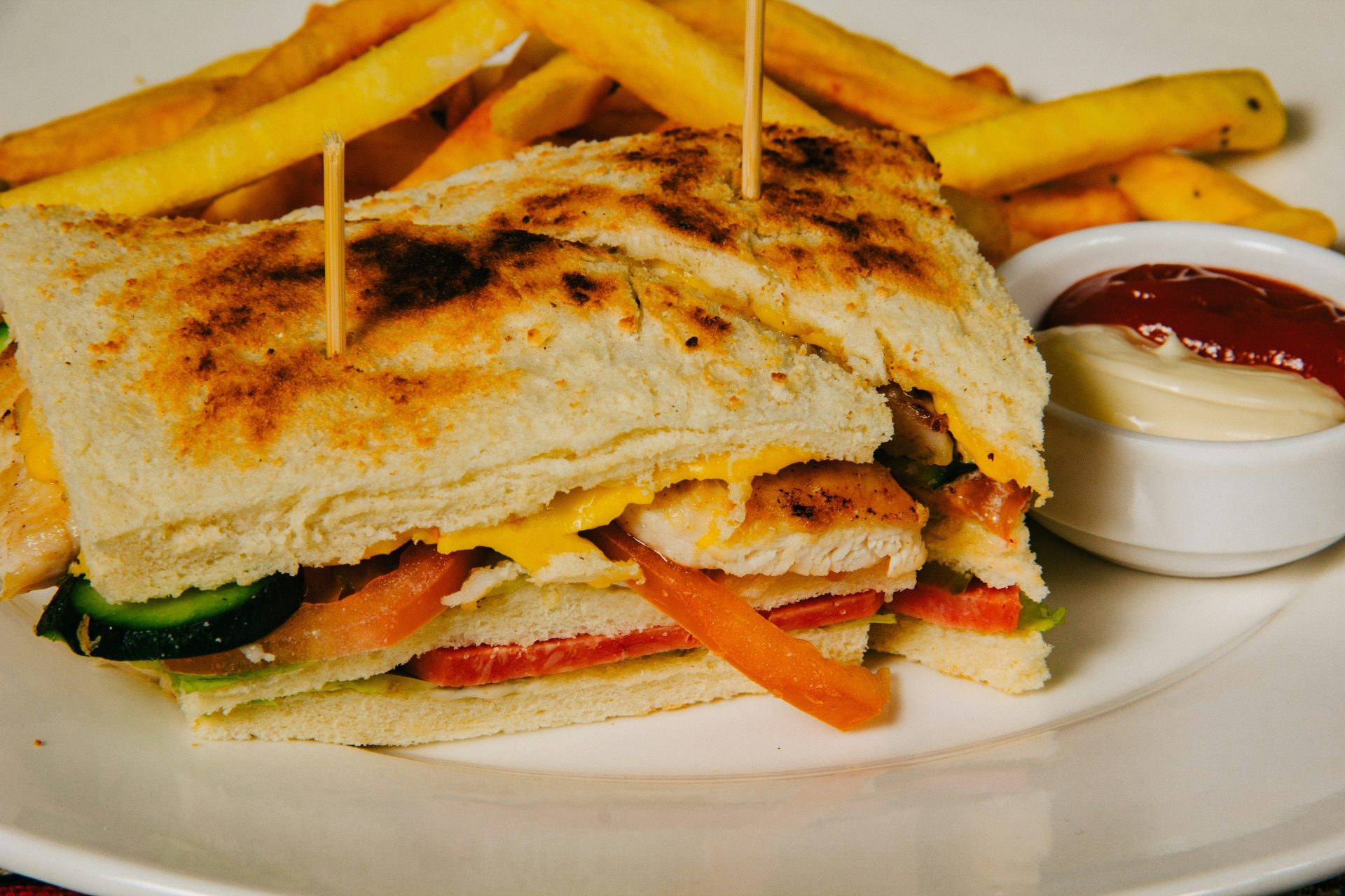 Grilled club sandwich with crispy golden fries.