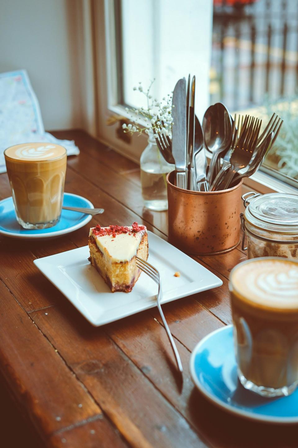 Cheesecake and lattes by window light.