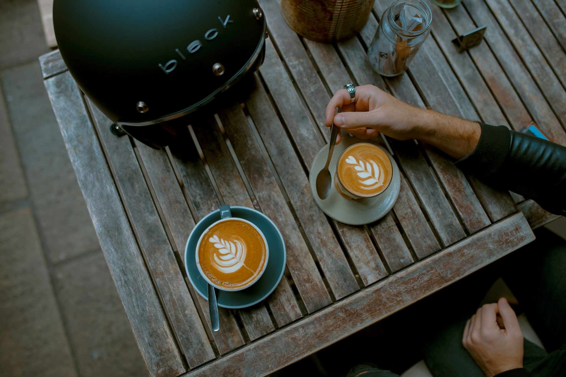 Outdoor table with lattes and black helmet.