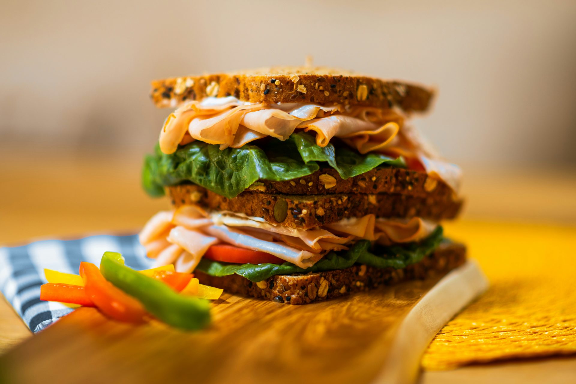 Stacked deli sandwich with colorful bell peppers.